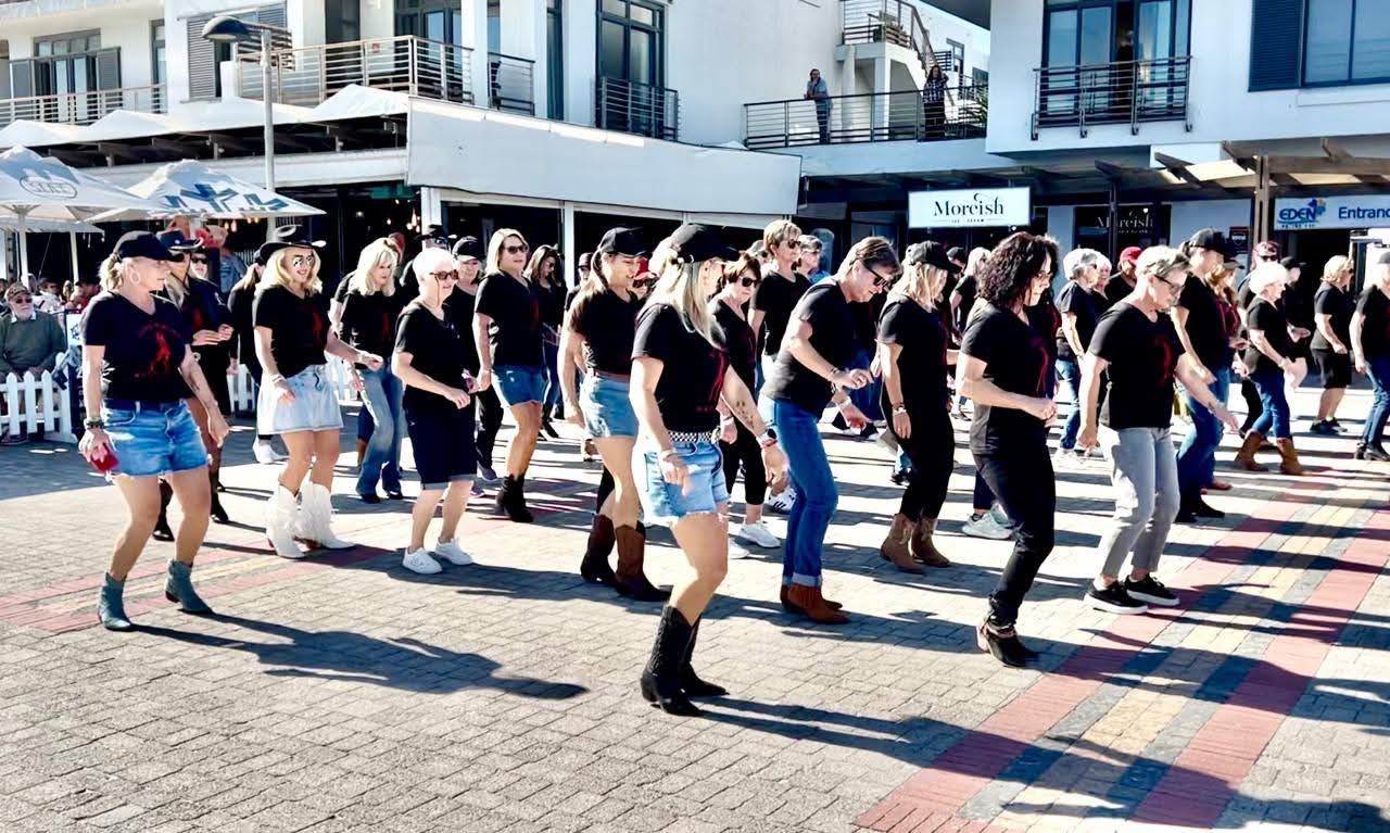 Line & Wine members line dancing together outdoors in club shirts and boots