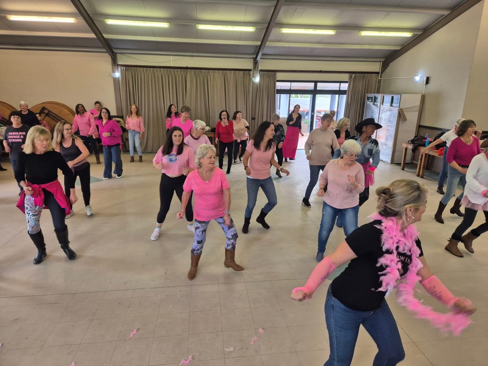 Line & Wine dancers in pink and black following steps together in a hall
