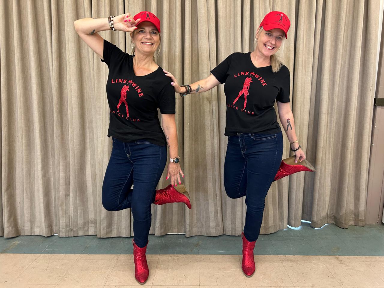 Two Line & Wine dancers posing in matching red boots and caps