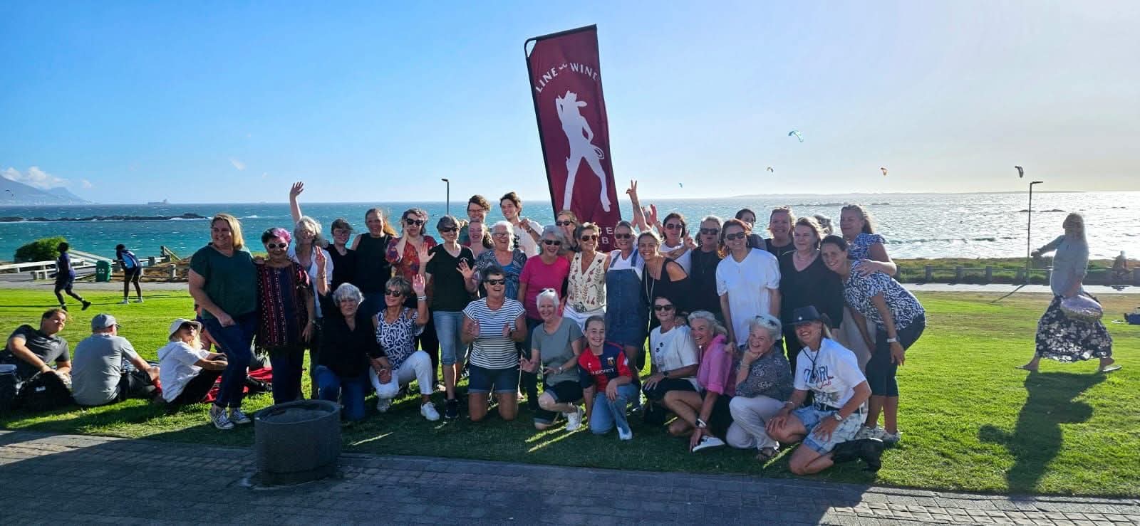 Line & Wine group gathered beside their club banner overlooking the sea
