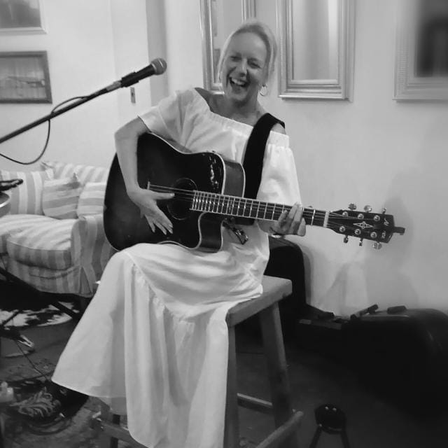 Michelle Schmidt smiling and playing guitar
